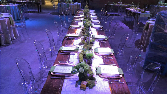 a wedding reception dinner table with centerpiece and transparent chairs