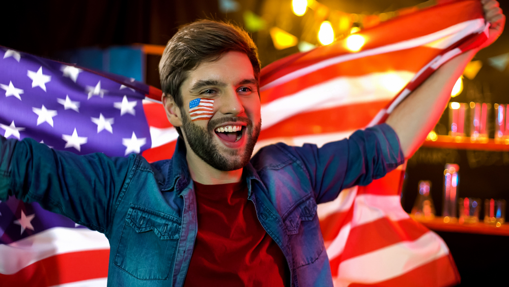 guy holding USA flag behind him and shouting happily