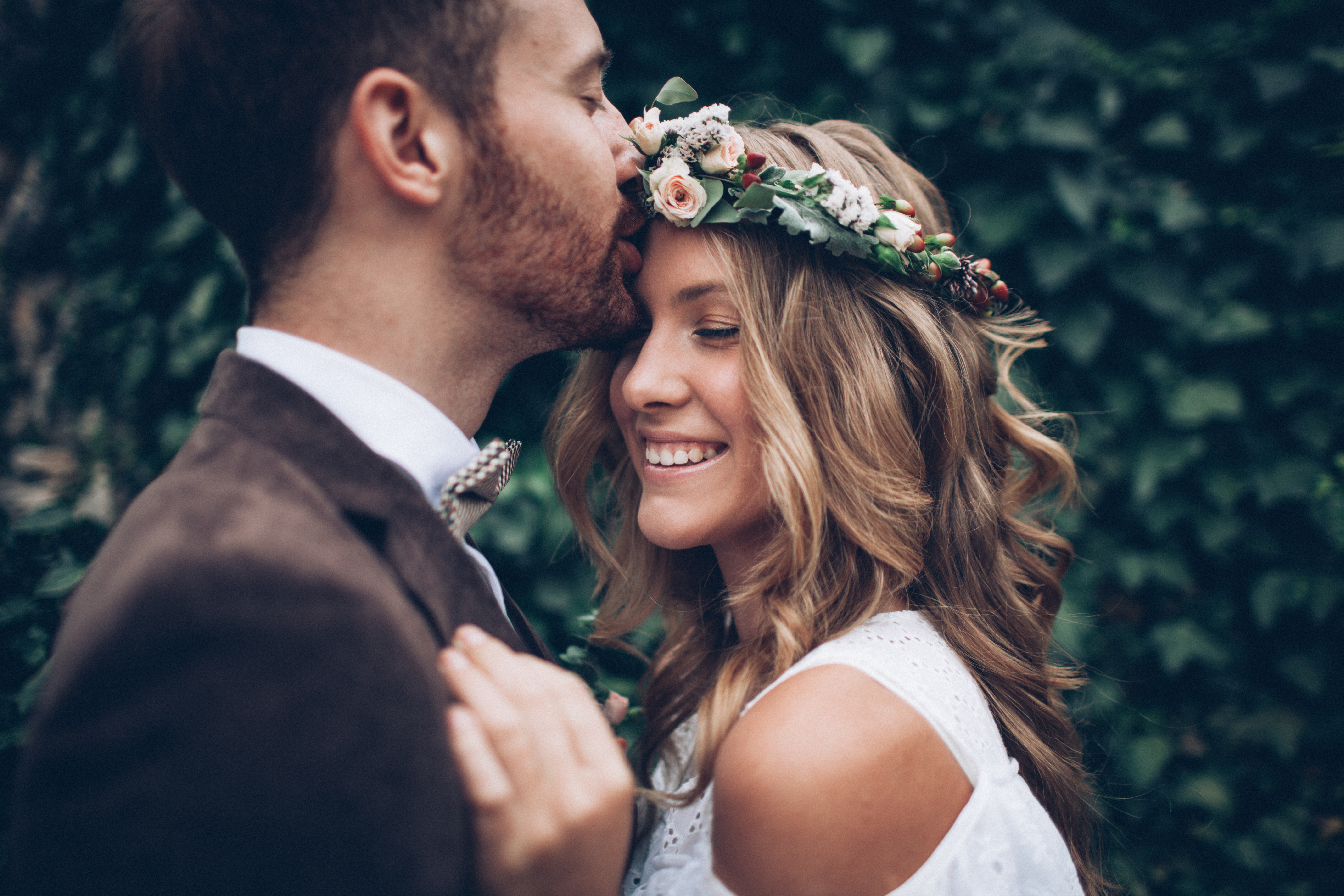 bridal shoot - groom is kissing his smiling bride on the forehead