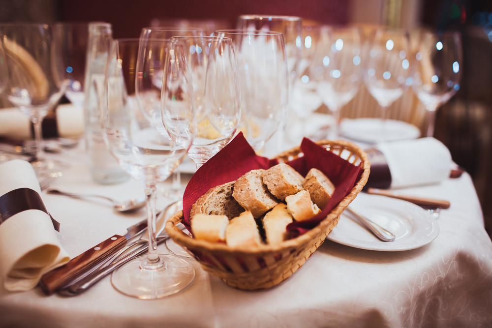 Classy wine and champagne glasses with a bread basket on a white linens.