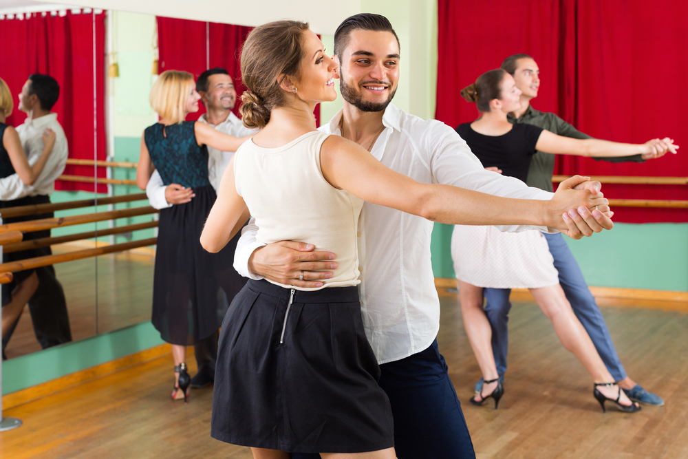 Three couples learn how to waltz in a studio.