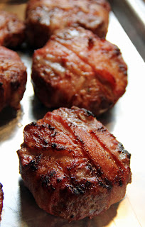 Bacon-wrapped burger patties on a tray.