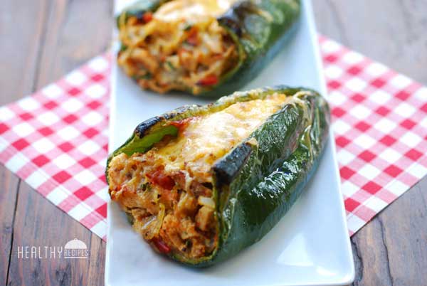 Two stuffed poblano peppers it on a tray on a picnic bench.