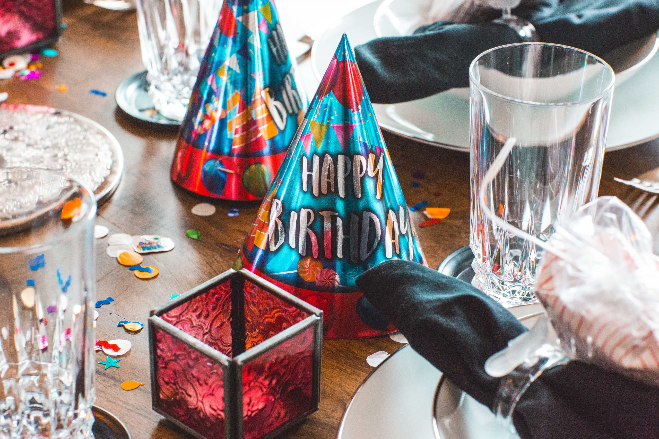 Birthday decorations and party hats on a table with glitter and confetti.